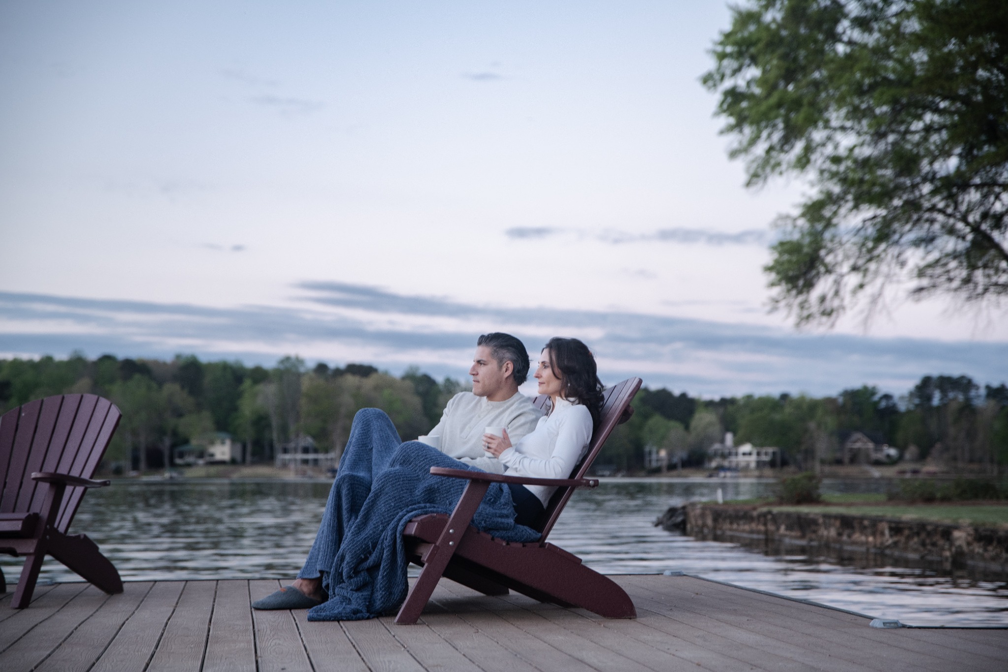 Couple relaxing in Adirondack chairs beside the lake at The Retreat at Lake Oconee